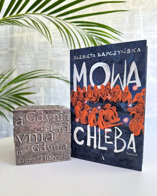 Zdjęcie książki "Mowa chleba" obok kostki Nagrody Literackiej Gdynia