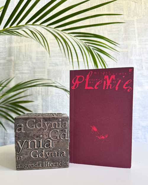 Zdjęcie książki "Plemię" obok kostki Nagrody Literackiej Gdynia