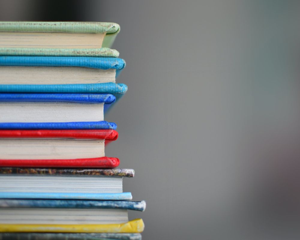 Kolorowe książki leżące na sobie, równo ułożone. 