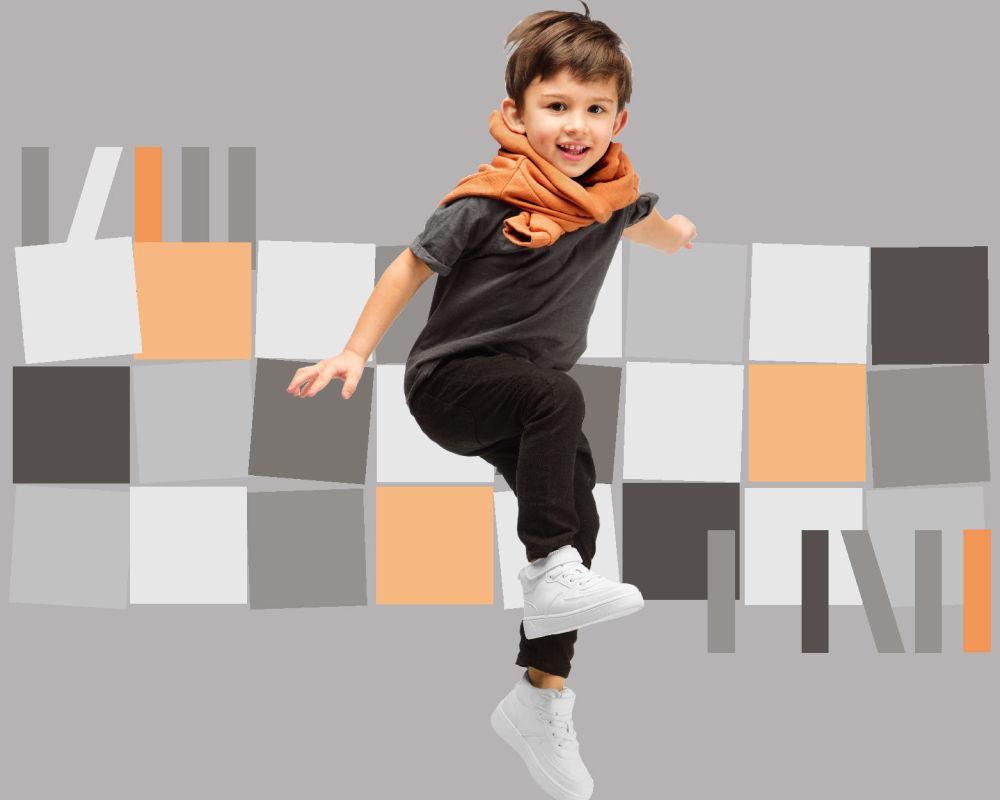 Tańczący chłopiec na tle mozaiki z szarych, białych, czarnych i beżowych elementów. 
