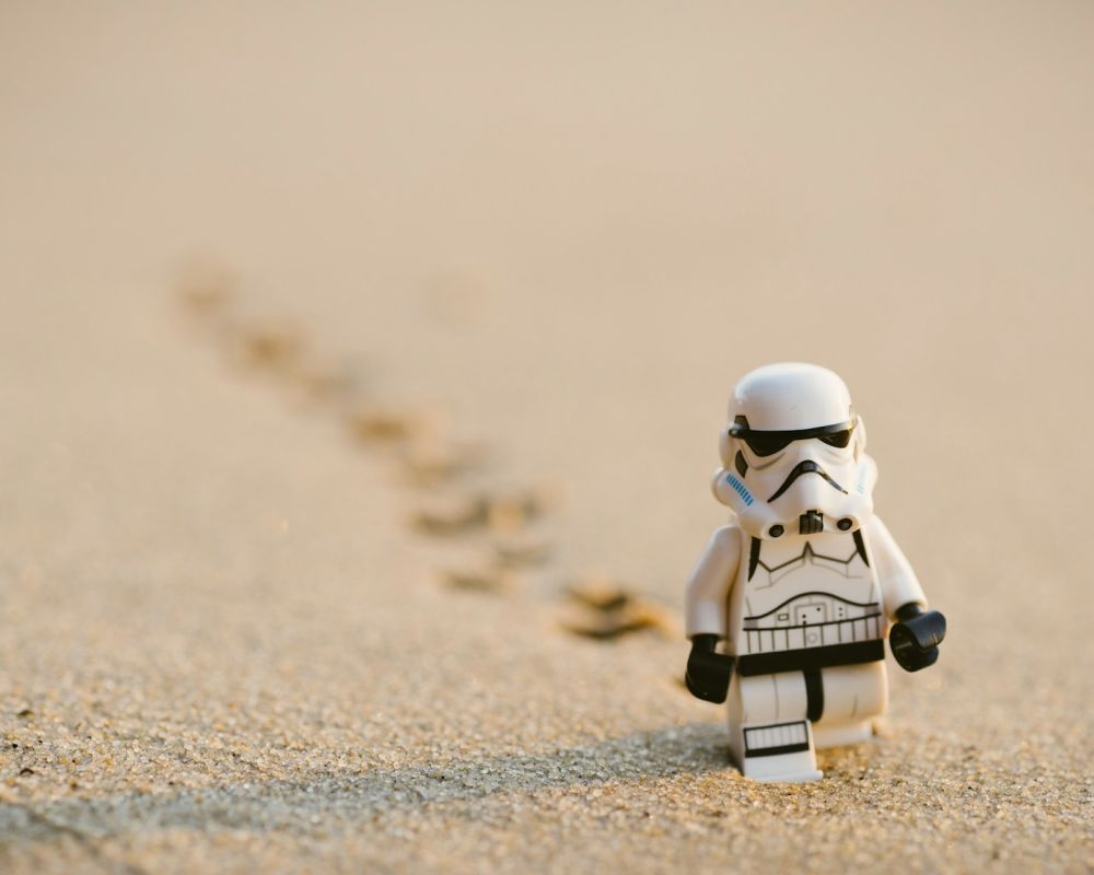 Figurka Lego Szturmowca ze Star Wars idącego po piasku i zostawiającego ślady.