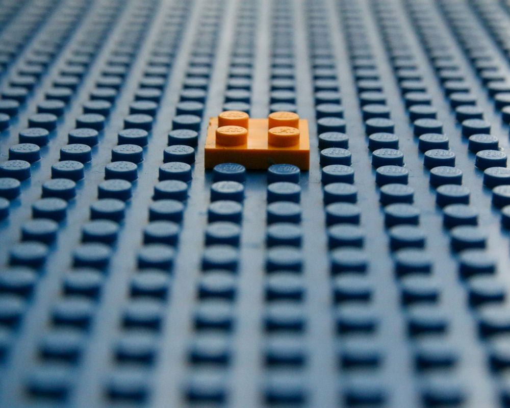 Mały, pomarańczowy klocek przyczepiony do dużego niebieskiego klocka Lego