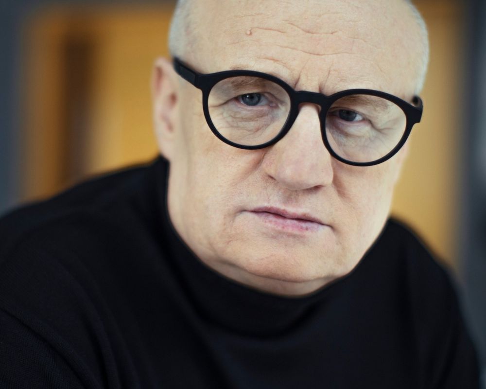 Maciej Siembieda. Mężczyzna w średnim wieku, w okularach z grubymi, czarnymi oprawkami.