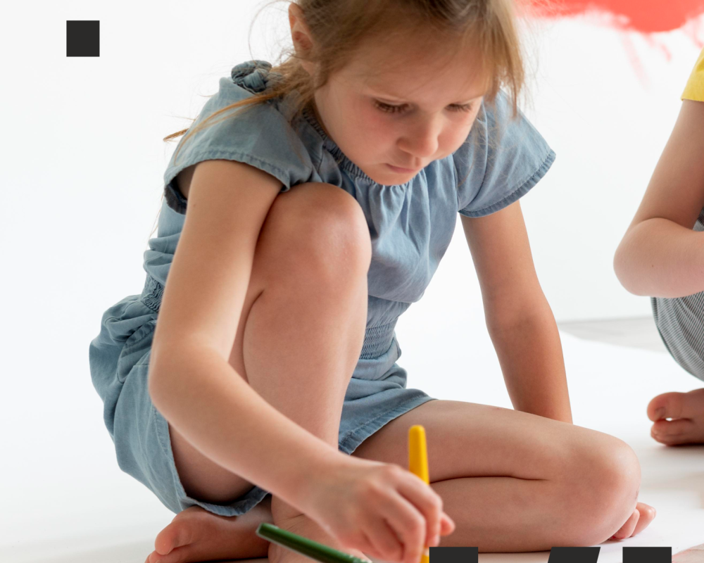 Siedząca na podłodze, malująca dziewczynka.