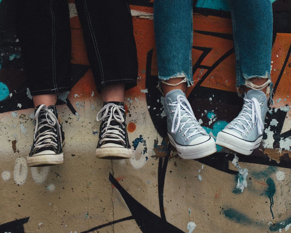 Obute w trampki nogi zwisające z murku