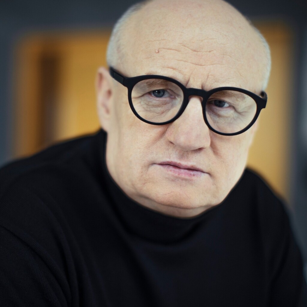 Maciej Siembieda. Mężczyzna w średnim wieku, w okularach z grubymi, czarnymi oprawkami.