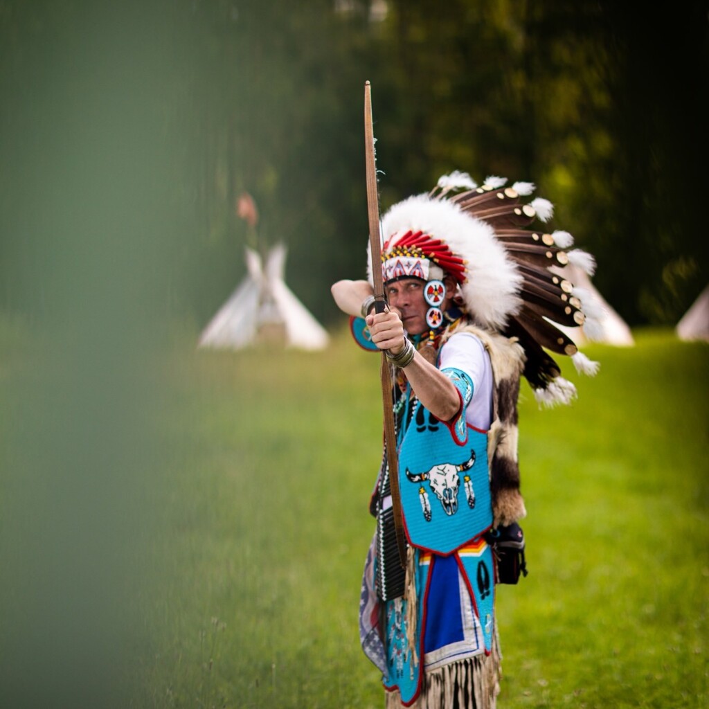 Mężczyzna przebrany za Indianina i strzelający z łuku