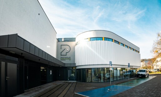 Przystań Łowicka 51. Nowoczesny, dwupiętrowy budynek. Na dole przeszklony, u góry z białą elewacją.