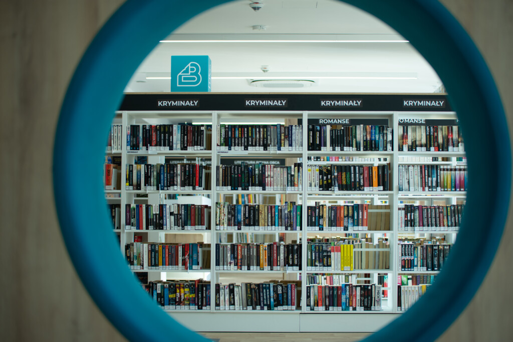 Biblioteka Cisowa. Regał z książkami widziany zza okrągłego siedziska do wypoczynku.