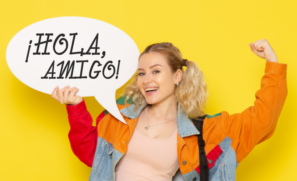 Ilustracja przedstawia młodą kobietę, trzymającą w prawej dłoni komiksowy dymek z napisem "Hola, amigo!", lewą rękę ma uniesioną w górę z zaciśniętą pięścią w geście radości..