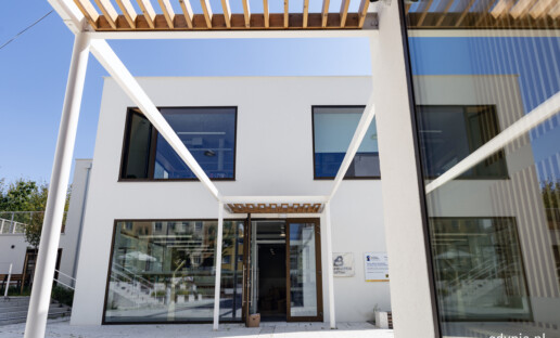 Biblioteka Witomino z zewnątrz, od strony głównego wejścia. Prostokątny, biały budynek z dużymi oknami.