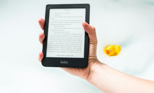 Na białym tle trzymany w dłoni czytnik ebooków, W tle gumowa kaczuszka.