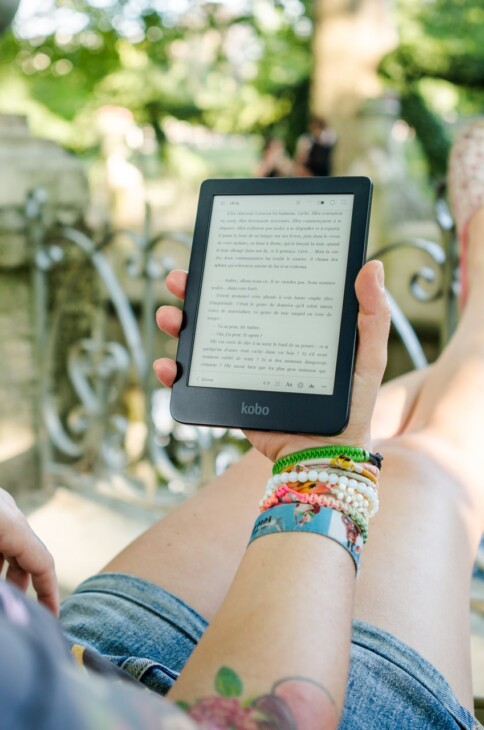 Dziewczyna siedząca na leżaku i czytająca ebooka na czytniku w ogrodzie