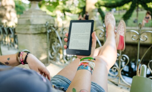 Dziewczyna siedząca na leżaku i czytająca ebooka na czytniku w ogrodzie