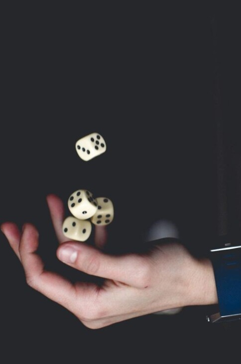 Ręka podrzucająca kostki do gry