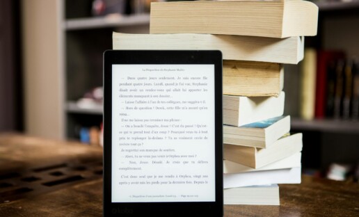 Czytnik ebooków, za którym stoi góra książek