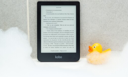 Czytnik ebooków stojący na krawędzi wanny, oparty o ścianę. Po prawej stronie stoi mała, żółta, gumowa kaczuszka.