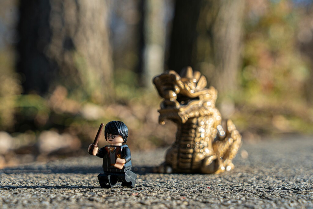 Figurka Lego przedstawiająca Harrego Pottera. Z tyłu za nią figurka smoka.