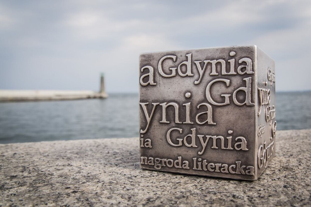 Nagroda Literacka GDYNIA - statuetka w kształcie kostki, stojąca na falochronie na Bulwarze Miejskim w Gdyni. W tle widać morze.