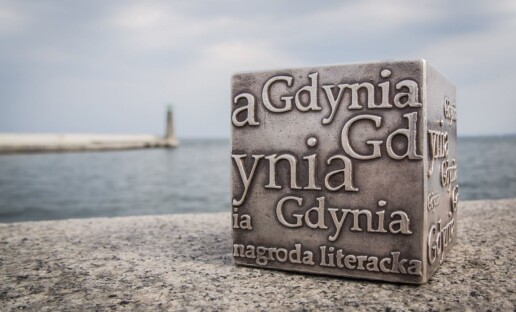 Nagroda Literacka GDYNIA - statuetka w kształcie kostki, stojąca na falochronie na Bulwarze Miejskim w Gdyni. W tle widać morze.