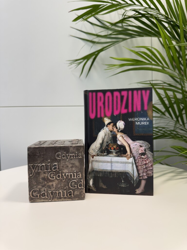 Zdjęcie książki "Urodziny" koło kostki Nagrody Literackiej Gdynia