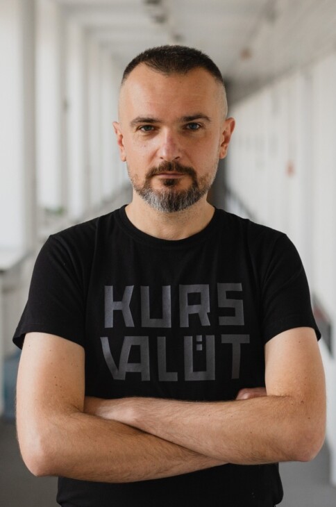 Marcin Gaczkowski - młody mężczyzna z zarostem na twarzu. Stoi ze splecionymi rękoma. Ma na sobie czarną koszulkę.