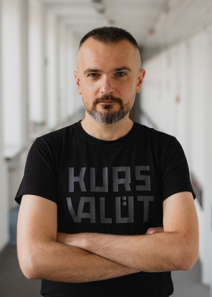 Marcin Gaczkowski - młody mężczyzna z zarostem na twarzu. Stoi ze splecionymi rękoma. Ma na sobie czarną koszulkę.