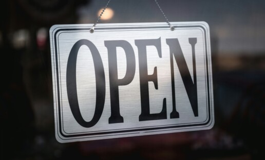 biała tabliczna z czarnym napisem "open" wywieszona na szybie