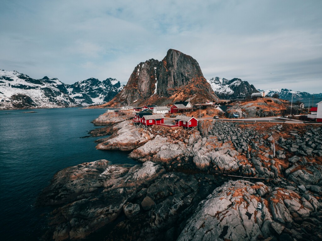 Czerwony, niski norweski domek na skałach przy fjordzie.